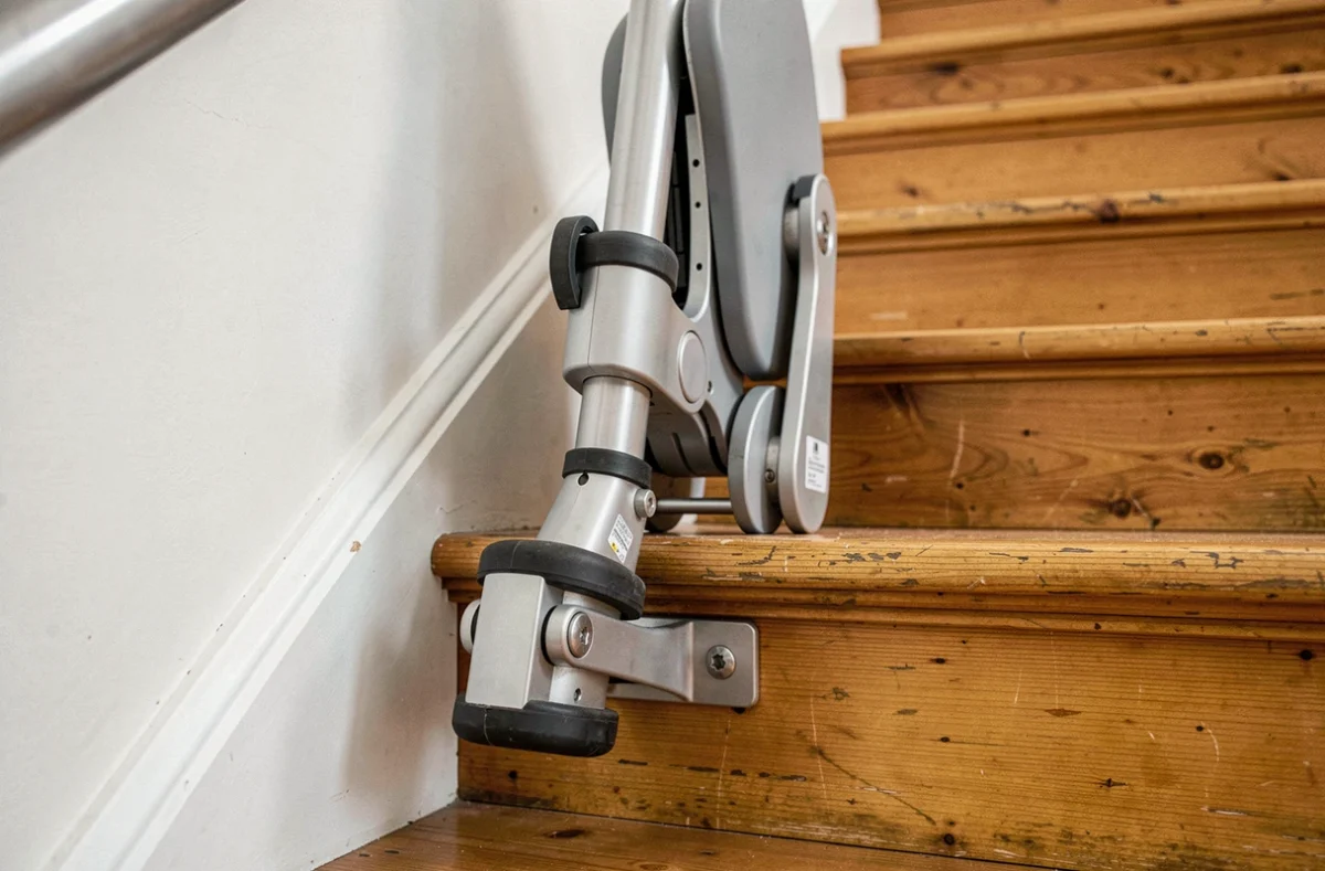 Détail du système de fixation sans travaux d'un monte escalier sur une marche en bois dans une maison individuelle