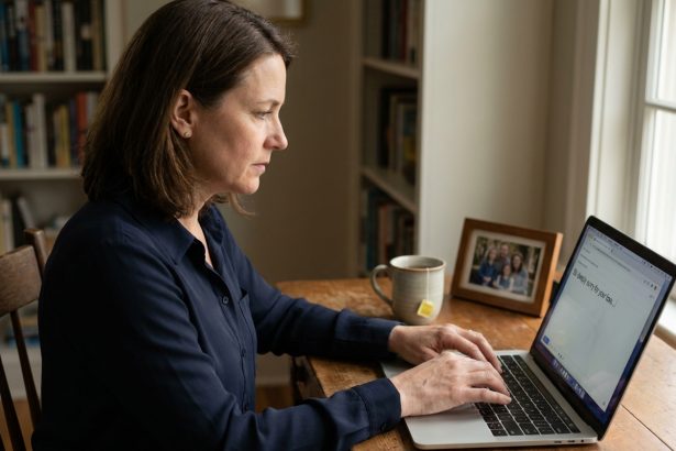 Femme endeuillée rédigeant un message de remerciement numérique après un décès sur son ordinateur portable à domicile