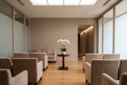 Salle d'accueil d'un funérarium moderne avec fauteuils beige, parquet en bois et orchidée blanche sur table, ambiance sobre et apaisante